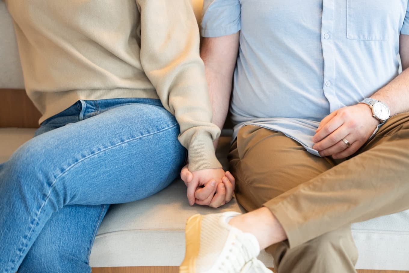 A couple sitting close, holding hands.